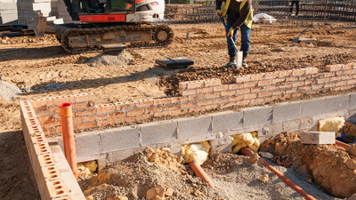 housebuilding plot drainage with groundworker and excavator in the background