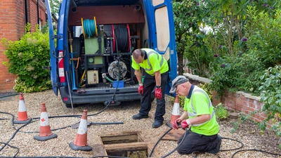 Drainage jetting team with manhole open and rodding equipment to unblock drains