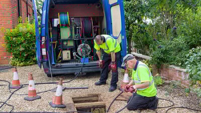 Drainage jetting team with manhole open and rodding equipment to unblock drains