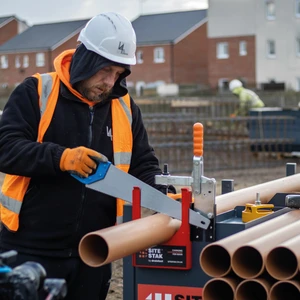 Construction worker cutting drainage pipe on a SiteStak workstation